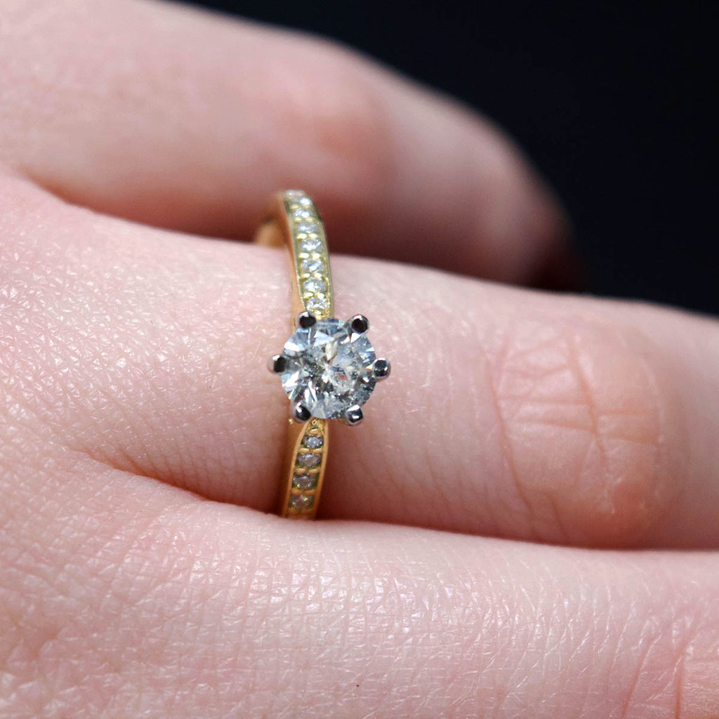 18ct Yellow Gold Solitaire Diamond Engagement Ring with Diamond Shoulders on hand, sold at Nouveau Jewellers in Manchester